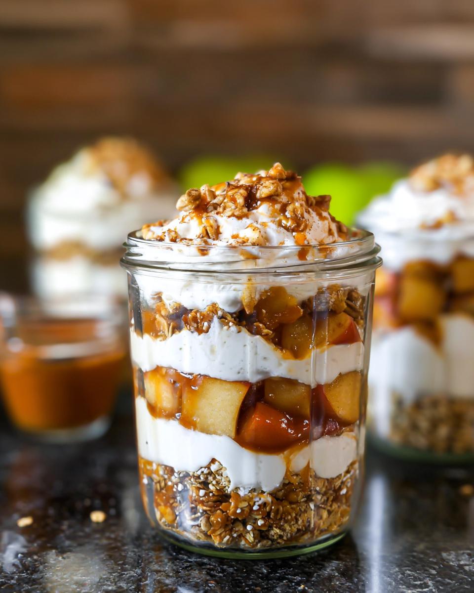 Close-up of Caramel Apple Trifle Layers in a glass jar, showing distinct layers of cream, apples, and granola.